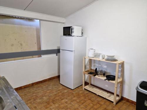 a kitchen with a white refrigerator and a small table at Cayenne Centre Payé Eco Confort in Cayenne