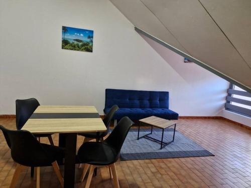 a living room with a table and a blue couch at Cayenne Centre Payé Eco Confort in Cayenne