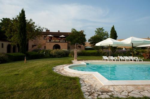 basen z leżakami i parasolami na dziedzińcu w obiekcie Agriturismo Il Poderino w mieście Asciano