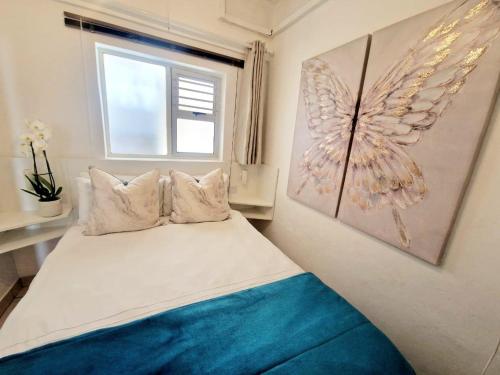 a bedroom with a bed with a window and a painting at OCEAN GEM-Back up power, Families & Couples, Umdloti in Umdloti
