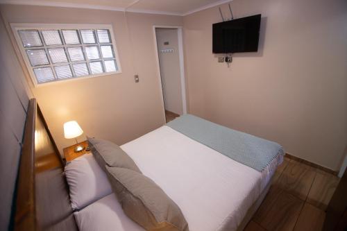 Dormitorio pequeño con cama y TV en Hostal Terraza Recreo, en Viña del Mar