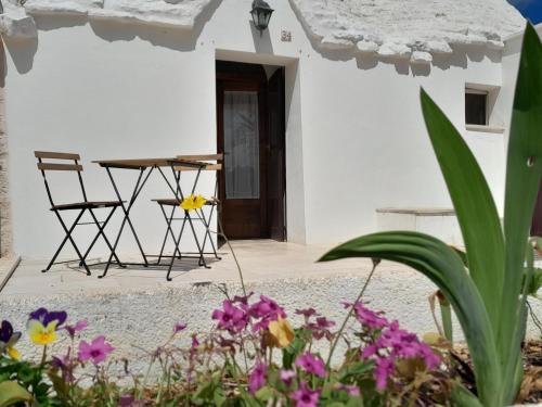 een patio met een tafel, stoelen en bloemen bij Trullo Il Giglio in Cisternino