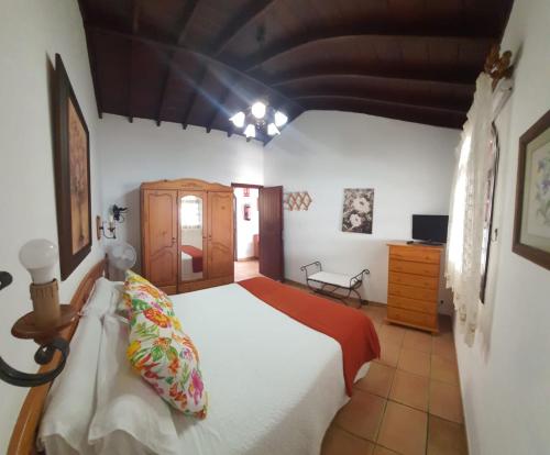 a bedroom with a white bed and a wooden cabinet at Casa Domingo Simón in Fuencaliente de la Palma