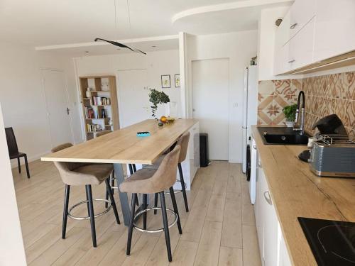 - une cuisine avec une table et des tabourets en bois dans l'établissement Hauteur d'Antibes 3 pièces vue mer et montagne Calanques, à Antibes