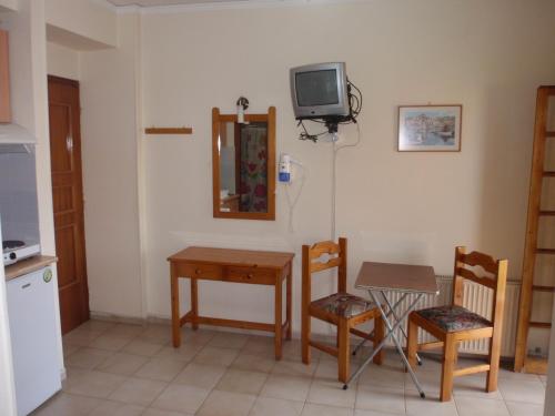 a kitchen with a table and a tv on the wall at Vazakas Rooms in Mytilini