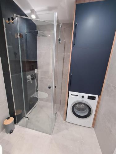 a washing machine in a bathroom with a shower at Apartament przy tężni in Augustów
