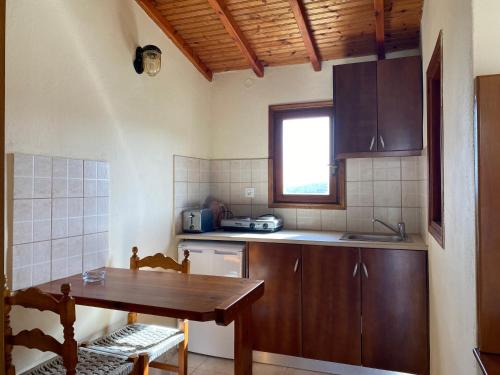 a kitchen with a wooden table and a table and a window at Valmas village in Skiathos Town