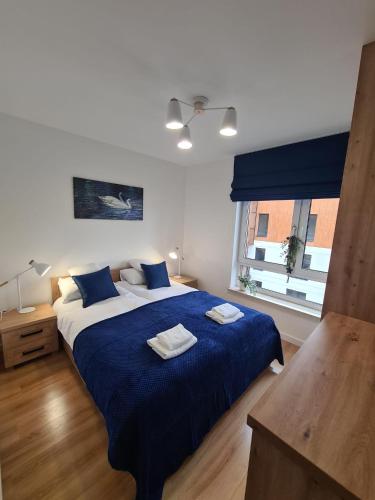 a bedroom with a bed with blue sheets and a window at Apartament przy tężni in Augustów