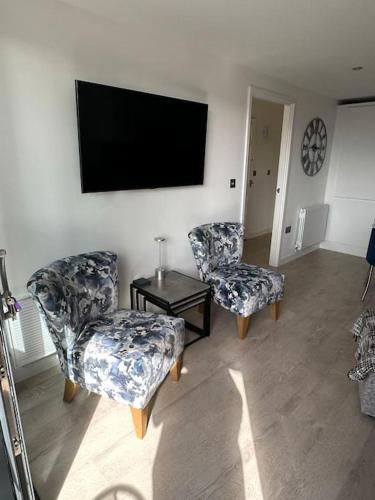 a living room with two chairs and a flat screen tv at Polmear Apartments, Charlestown in Charlestown