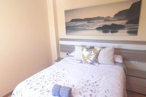 a bedroom with a bed with a painting on the wall at Apartamento Playa Foz in Foz