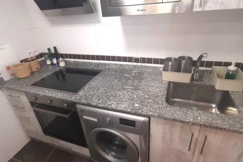 a kitchen with a sink and a washing machine at Apartamento Playa Foz in Foz