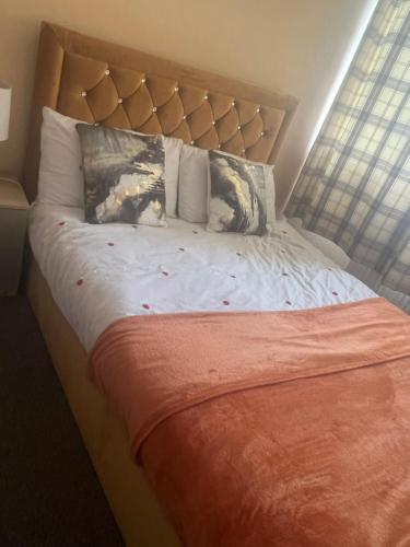 ein Bett mit einer orangefarbenen Decke und Kissen darauf in der Unterkunft Modern 3 Bed House for 6 guests in Nevendon