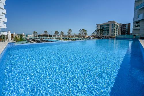 una grande piscina blu con edifici sullo sfondo di Aqua Vista Infinity Apartament Lux Vedere La Mare - Resort & Spa a Mamaia Nord - Năvodari