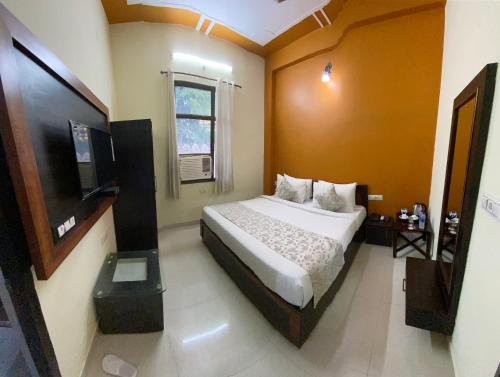 1 dormitorio con 1 cama y TV de pantalla plana en The Tiger Heritage, en Sawāi Mādhopur