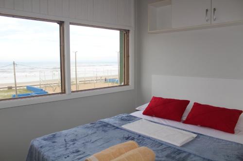 ein Schlafzimmer mit einem Bett mit Blick auf den Strand in der Unterkunft Apartamento Vista para Beira-Mar e Calçadão centro de Tramandaí in Tramandaí