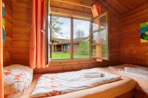 a bedroom with a bed in a log cabin with a window at Hüssli Numero 1 in Hayingen