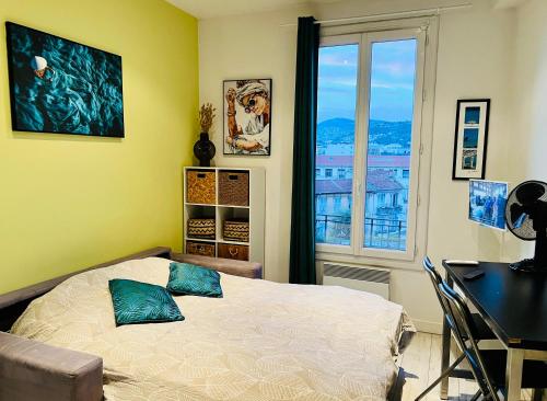 1 dormitorio con cama, escritorio y ventana en Élégant Studio à 1 minute du centre, en Niza
