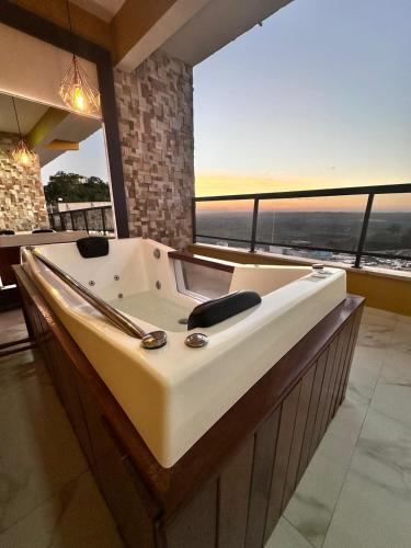 a bath tub in a room with a large window at ECOLETRAS APART - SÃO THOMÉ DAS LETRAS Mg in São Thomé das Letras