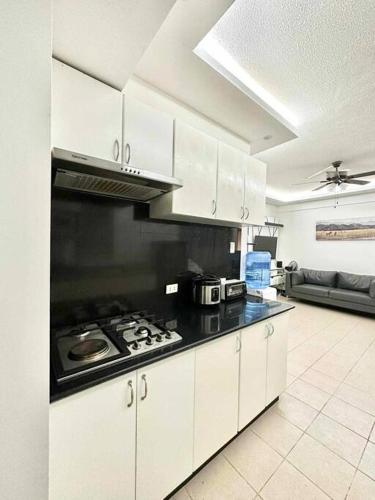 a kitchen with white cabinets and a stove top oven at 3BR Fully furnished with Balcony in Davao City
