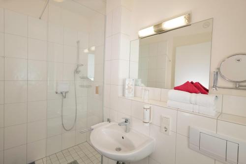 ein weißes Bad mit einem Waschbecken und einer Dusche in der Unterkunft Hotel Moseldomizil in Mülheim an der Mosel