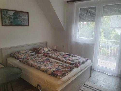 1 dormitorio con 1 cama en una habitación con 2 ventanas en Farkas Apartmanok, en Balatonlelle