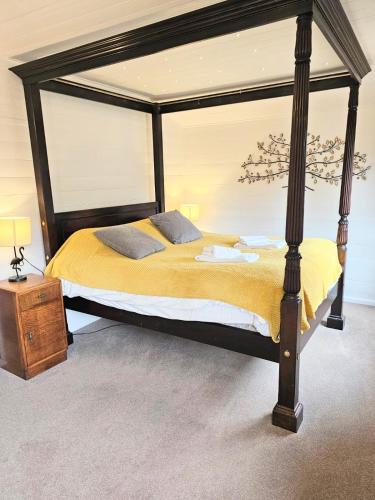 a bedroom with a large canopy bed with yellow sheets at Magpie 1 Hot Tub HuntersMoon-Warminster-Bath-Wiltshire in Warminster