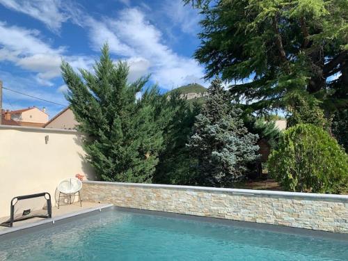 - une piscine avec un mur en pierre et des arbres dans l'établissement Superbe Villa Centre-ville Millau, à Millau