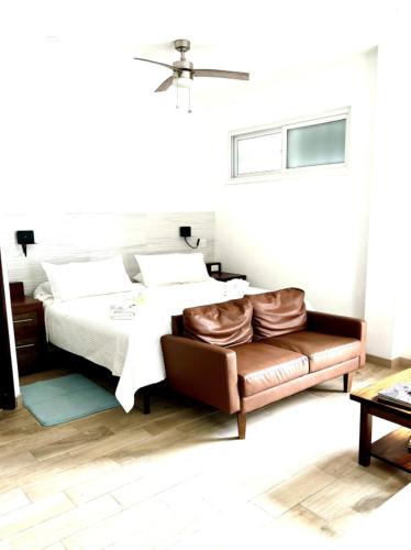 Un dormitorio con una cama y un sofá de cuero. en La Vida Perezosa, en Caye Caulker