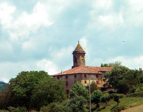 an old building with a clock tower on a hill at Ultzama in Iráizoz