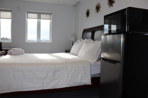 AMR Hotel Inc في سان جيروميه: غرفة نوم بسرير ابيض وثلاجة