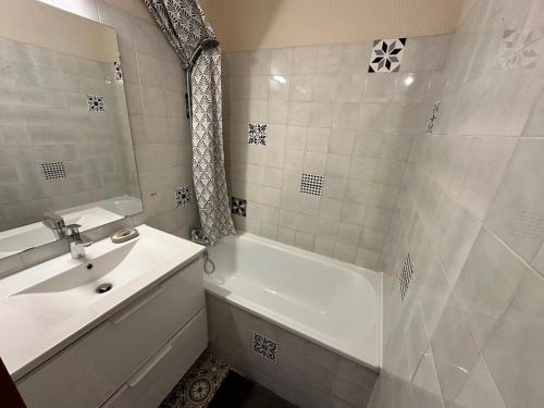 La salle de bains blanche est pourvue d'un lavabo, d'une baignoire et d'une douche. dans l'établissement Joli 2 pièces, vue montagne, balcon Sud, WIFI, kit bébé - FR-1-515-181, à Villard-de-Lans