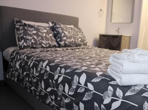 a bed with a black and white comforter and towels at AMR Hotel Inc in Saint-Jérôme
