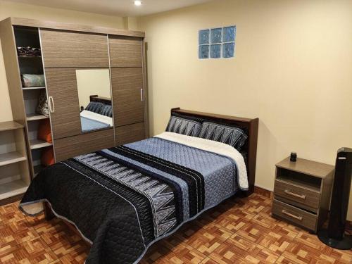 Warm House Near the Airport Callao في ليما: غرفة نوم بسرير كبير ومرآة
