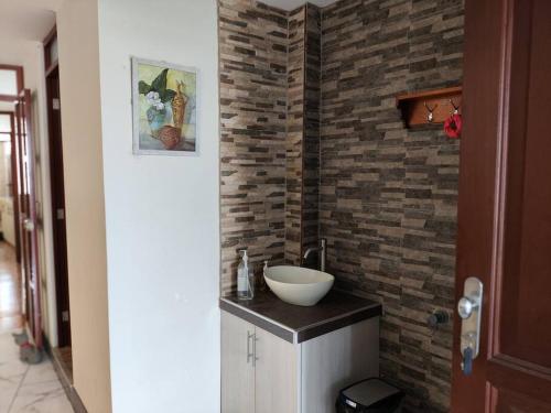 La salle de bains est pourvue d'un lavabo et d'un mur en briques. dans l'établissement Warm House Near the Airport Callao, à Lima