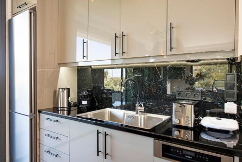 a kitchen with white cabinets and a sink at Villa Ilianthi in Kalamitsi