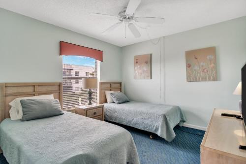 a bedroom with two beds and a window at Cape Winds Resort in Cape Canaveral