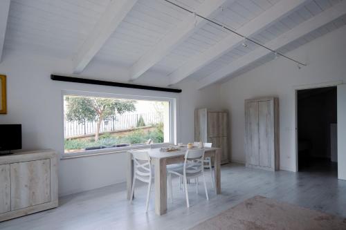 a white dining room with a table and a window at La Meridiana Casa Vacanze in San Vitale