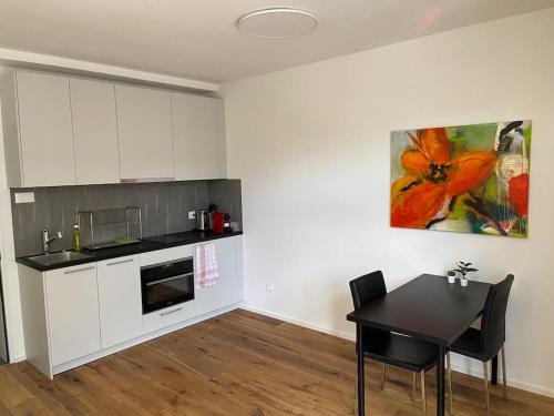 Modernes Appartement in Wald في Wald: مطبخ بدولاب بيضاء وطاولة ولوحة