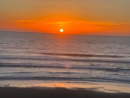 a sunset on the beach with the ocean at GoldBeach House in Pataias