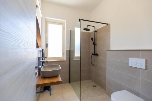 La salle de bains est pourvue d'un lavabo et d'une douche en verre. dans l'établissement Villa Serenità - with private pool and ocean view, à Ricadi