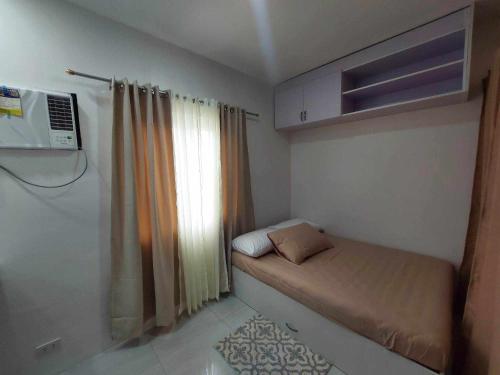um pequeno quarto com uma cama e uma janela em Twin Hearts Residences Unit 215 em Roxas