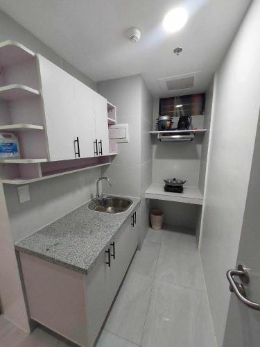 a small kitchen with white cabinets and a sink at Twin Hearts Residences Unit 215 in Roxas City