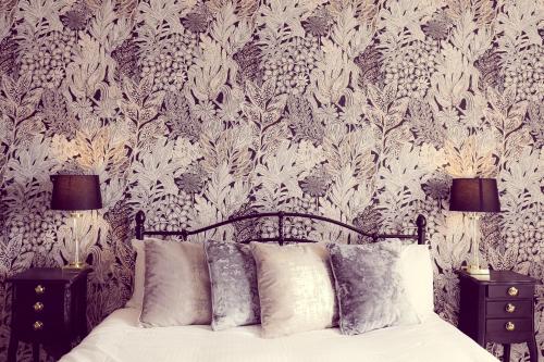 1 dormitorio con 1 cama y papel pintado con motivos florales en The Sun Inn en Ulverston