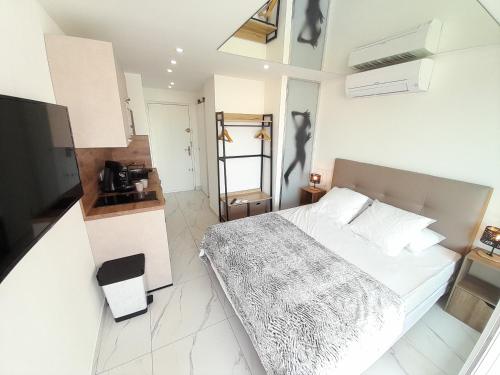 une chambre avec un grand lit blanc et une cuisine dans l'établissement Studio Village Naturiste Port Venus Sensation, au Cap d'Agde