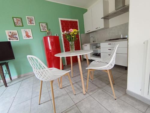 uma cozinha com uma mesa e 2 cadeiras e um frigorífico vermelho em Oasi Santaquilina em Rimini