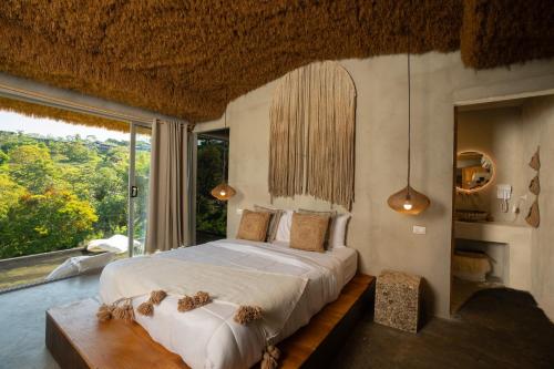 ein Schlafzimmer mit einem Bett und einem großen Fenster in der Unterkunft Casa Lamia in Manuel Antonio