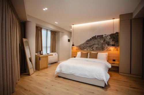 ein Schlafzimmer mit einem weißen Bett und einem Gemälde an der Wand in der Unterkunft Oro Inn Hotel in Shkodra
