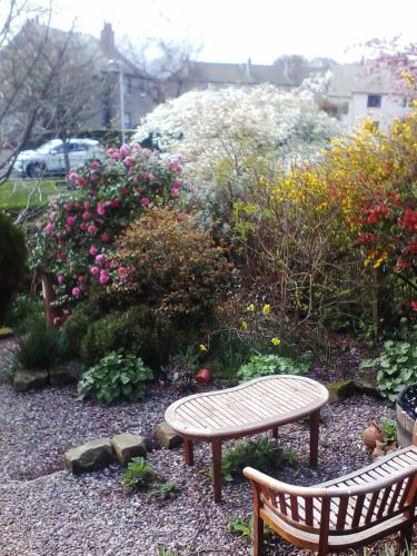 a bench sitting in a garden with flowers at The Spindle Guest Rooms in St. Andrews