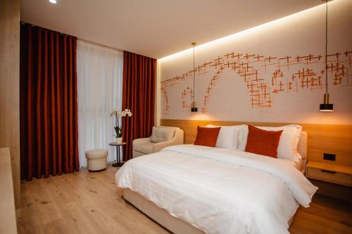 a bedroom with a large white bed and a chair at Oro Inn Hotel in Shkodër