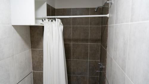 La salle de bains est pourvue d'une douche avec rideau de douche blanc. dans l'établissement AP138 3bDepartamento micro centro Parana 3b, à Paraná